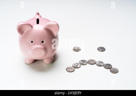 Hohe Betrachtungswinkel von rosa Sparschwein in der Nähe von Münzen über graue Oberfläche Stockfoto