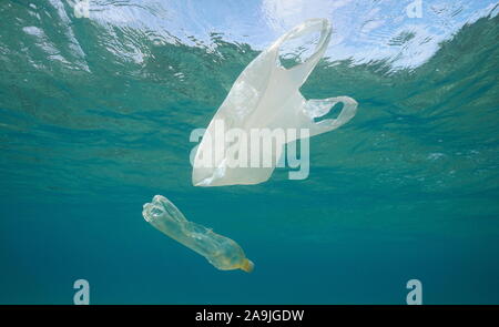 Unterwasser Umweltverschmutzung, eine Plastiktüte und eine Flasche hilflos unterhalb der Wasseroberfläche im Meer Stockfoto