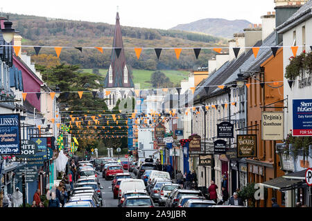 Pubs, Geschäfte, Hotels und Restaurants auf einer Halloween dekoriert Straße in Kenmare, County Kerry, Irland. Die Heilig-Kreuz-Kirche in der Ferne. Stockfoto