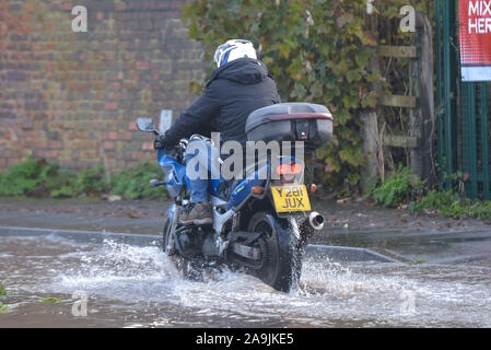 Tewkesbury, Gloucestershire, Vereinigtes Königreich. November 2019. Ein Motorradfahrer fährt seine Beine hoch, während er sich durch Überschwemmungen im Stadtzentrum von Tewkesbury navigiert, die von schweren Überschwemmungen heimgesucht wurden, als der Fluss Avon seine Ufer geplatzt hat. Der Flussspiegel steigt weiter an und wird voraussichtlich am späten Samstagnachmittag über 12 Meter über dem normalen Flussniveau steigen. Bild aufgenommen am 16.11.2019. Quelle: Stop Press Media/Alamy Live News Stockfoto