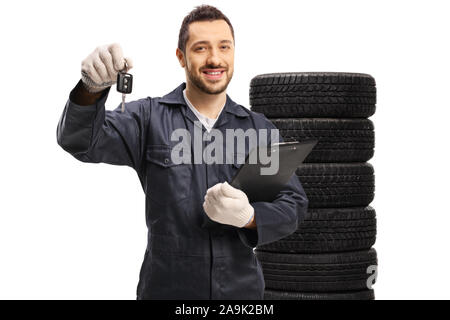 Autom. Halten Ein Auto keynand mecahanic in einen Reifenstapel hinter auf weißem Hintergrund Stockfoto