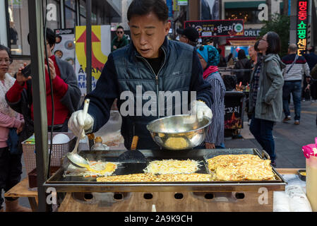 Seoul, Südkorea - November 04, 2019: ein Anbieter Kochen Gemüse Pfannkuchen zu essen in Myeongdong Straße Marktstand. Myeong Dong Bezirk ist ein beliebtes Stockfoto