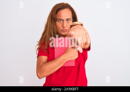 Mittleres Alter reife Frau mit einem Buch über isolierte Hintergrund zeigt mit dem Finger auf die Kamera und an Sie, Hand unterzeichnen, positiv und zuversichtlich gestu Stockfoto