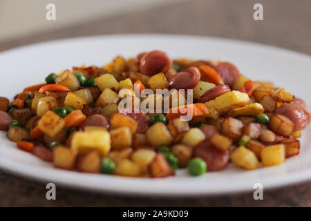 Beilage mit Omelette, Kartoffeln, Würstel, Karotten und Erbsen Stockfoto