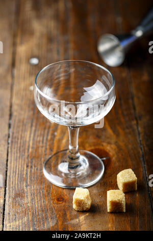 Eine leere cocktail Glas auf einem braunen Holz- Theke steht. rohrzucker Würfel Stockfoto