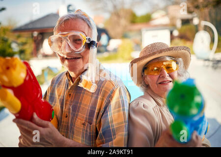 Senior verrückten Mann und Frau viel Spaß beim Spielen mit Wasser Pistole. Stockfoto