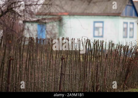 Alte ländliche Zaun wattle Zaun aus Holz- Stangen auf dem Hintergrund der Haus Stockfoto