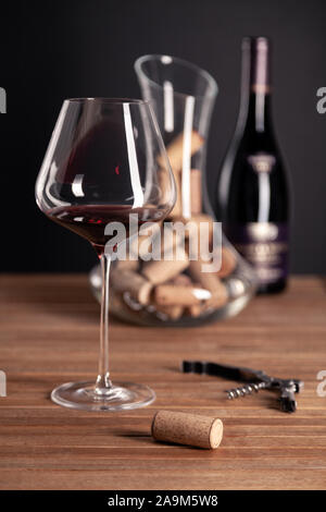 Crystal glänzend Rotwein Gläser, Flaschen, Korkenzieher, Flaschenöffner, Sommelier Messer, transparente Ölabscheider mit Korken auf hölzernen Tisch. Closeup, Vertikal, wählen Sie Stockfoto