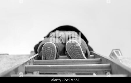 Low Angle View für einen Heimwerker Klettern auf einer Leiter. Stockfoto