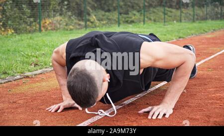 Junge passen Mann tun Push-ups am Morgen im Freien auf der Rennstrecke Stockfoto