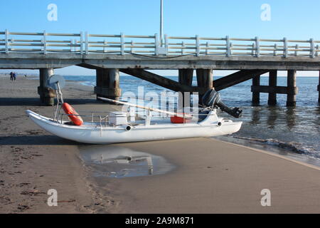 Eine Rettungsinsel. Ein Boot gestrandet am Sandstrand bei Tageslicht in der Versilia, Toskana, Italien geparkt oder Stockfoto