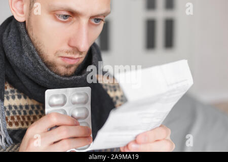 Mann mit Medikamenten Lesen der Anweisungen für den medizinischen Gebrauch der Droge. Stockfoto