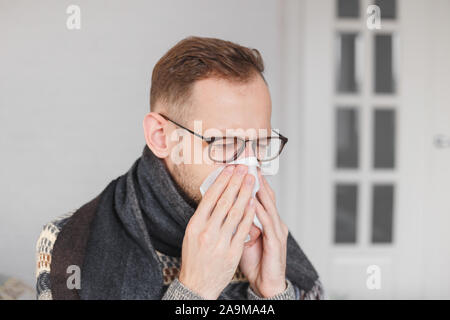 Jungen kaukasischen Mann eine Erkältung eingefangen, die Nase weht. Stockfoto