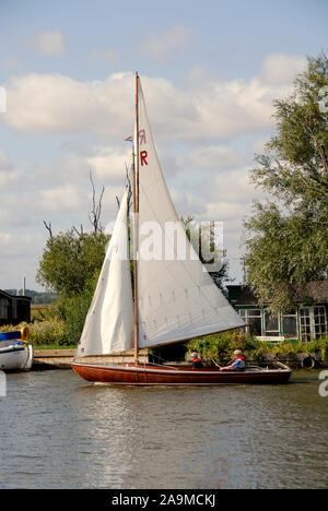 Zwei Leute auf einem kleinen sailng Yacht auf dem Fluss Thurne, Norfolk, England Stockfoto