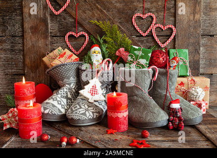 Gestrickte Stiefel mit kleine Geschenke und Süßigkeiten für Weihnachten Stockfoto