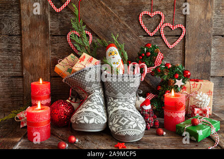 Gestrickte Stiefel mit kleine Geschenke und Süßigkeiten für Weihnachten Stockfoto