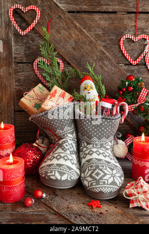 Gestrickte Stiefel mit kleine Geschenke und Süßigkeiten für Weihnachten Stockfoto