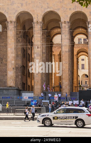 7-16-2019 in Tiflis Georgien - Protest vor dem Parlament mit Bildnis von Putin und pro-NATO-Banner - Sicherheit Zaun und Offiziere und Polizei Auto dr Stockfoto