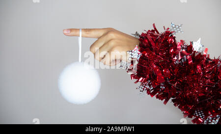 Eine Weihnachtsdekoration hängt vom Finger einer Frau. Woman's Hand gewickelt mit dekorativen Streamer auf das Neue Jahr. Stockfoto