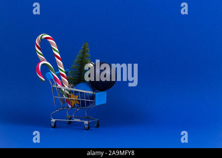 Mini Warenkorb mit kleinen Weihnachtsbaum, Weihnachten Deko weihnachtskugel Kugeln und Zuckerstangen auf marine blau hintergrund Stockfoto