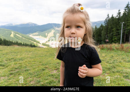 Kleines Mädchen mit Blume im Mund weg schauen auf Peak Stockfoto