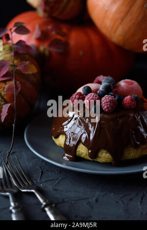 Gesunde hausgemachte Desserts. Traditionelle Dampf Pudding mit Schokoladenüberzug und Beeren und winterkürbisse auf schwarzem Hintergrund Kopie Raum Stockfoto