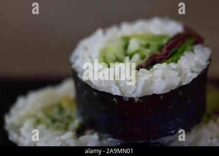 Japanisches Essen mit einer dicken Rolle futomaki, die mit Gemüse, Reis und Algen Blätter gefüllt ist ummantelt Stockfoto