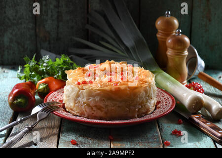 Herzhaftes Gebäck mit griescreme Teig. Hausgemachte Kuchen auf rote Platte auf Blau Holz- hintergrund Kopie Raum. Low Key noch Leben mit natürlicher Beleuchtung Nahaufnahme Stockfoto