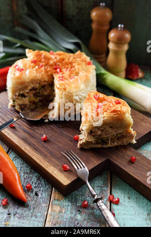 Herzhafte griescreme Gebäck Kuchen mit Hähnchen und Gemüse dekoriert mit Granatapfel Samen auf Eiche dunkel Platine senkrechte Stockfoto