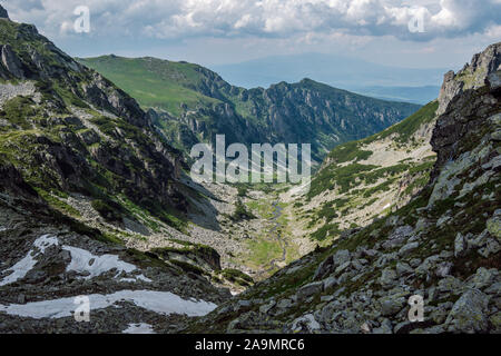 Panoramablick auf einem schönen grünen Tal mit einem fließenden Fluss durch IT- und steile, felsige Hänge, Rila Gebirge, Bulgarien. Stockfoto