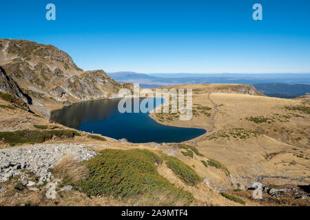 Blau Gletschersee mit steilen felsigen Ufern, die Niere See, Teil der Sieben Rila Seen und einem klaren blauen Himmel im Hintergrund, Rila Gebirge. Stockfoto