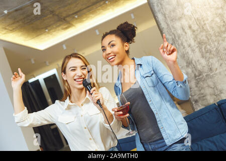 Weibliche Freunde in Party drinnen Spaß zusammen Karaoke singen Stockfoto