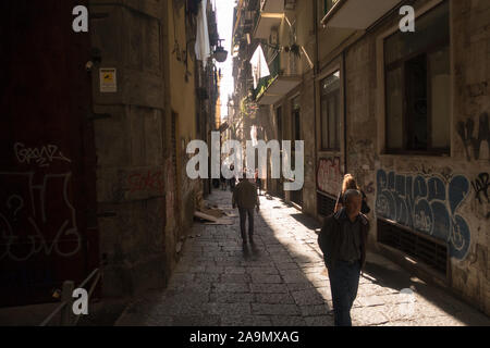 Sonne, die in einer schmalen Gasse im Stadtzentrum von Neapel durch die Gebäude kommt Stockfoto