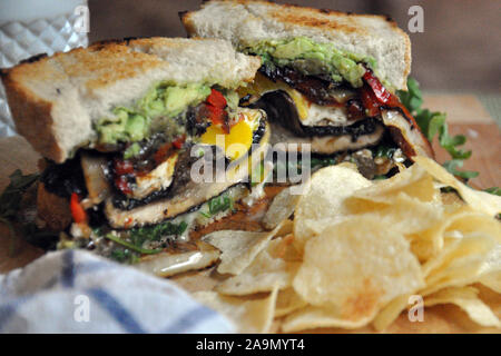 Cheesy vegetarische Portabello Sandwich in der Hälfte mit Chips Stockfoto
