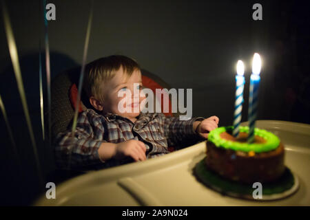 Kleinkind Junge lächelt am lit Geburtstag Kerzen auf kleinen Geburtstagskuchen Stockfoto