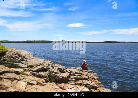Mann sitzt auf Felsen am Dyce Kopf felsigen Mantel auf Penobscot Bay Castine, Maine, USA Stockfoto