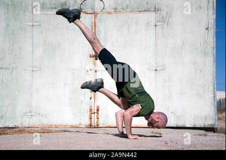 Mann in den Dreißigern mit Bart Yoga von einer alten grunge Wand. Stockfoto