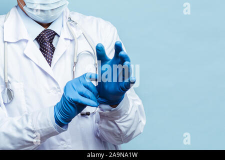 Arzt setzt auf Gummi Handschuhe, Gesundheitswesen und Medizin. Auf blauem Hintergrund isolieren Stockfoto