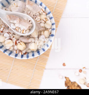 Lecker vier Stärkungsmittel Kraut Geschmack Suppe, Taiwanesische traditionelle Speisen mit Kräutern, schweinedickdarm auf weissem Holztisch, Nahaufnahme, Flach, Ansicht von oben. Stockfoto