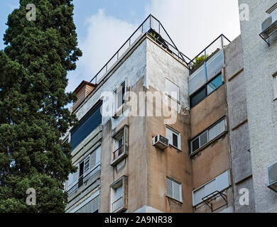 Vernachlässigt alte Beton Wohnanlage auf Tom Straße in Tel Aviv Israel anzeigen wetter Schäden und Form mit einem schönen Baum im Vordergrund. Stockfoto