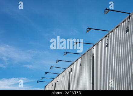 Straße Architektur Aussenleuchte gehängt und an der Wand des Gebäudes, das Blech mit blauem Himmel Hintergrund freitragende. Stockfoto