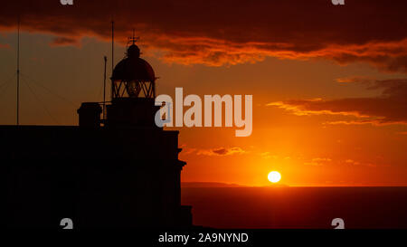 Cape vor Silhouette Leuchtturm gegen Orange Himmel Sonnenuntergang und Sonne am Horizont Ferrol La Coruña Galicien Spanien Stockfoto