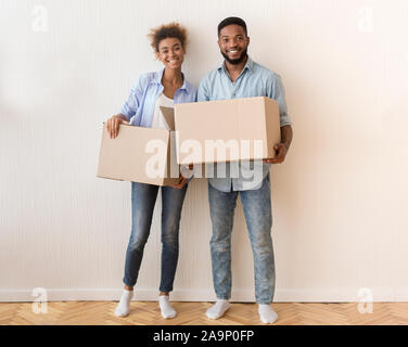 Ehegatten Holding Umzugskisten Gegen die Wand im neuen Haus stehend Stockfoto