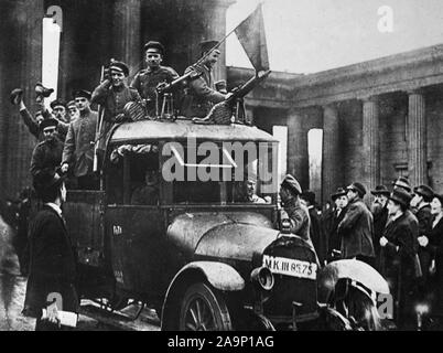 Deutsche Revolution - die Deutsche Revolution. Ein Motor der Arbeiter und Soldaten "Rat vorbei am Brandenburger Tor in Berlin. Der Motor ist mit einem Maschinengewehr bewaffnet und Flied die rote Flagge. Es führt auch eine Wache, bewaffnet mit einem Gewehr Ca. 1918-1919 Stockfoto