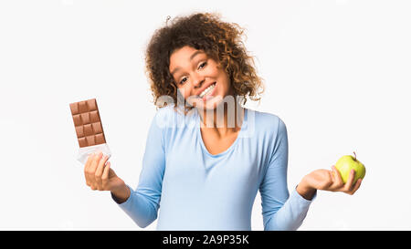 African-american schwangere Frau die Wahl zwischen Obst und Süßigkeiten Stockfoto