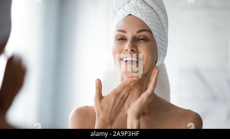 Happy lady Suchen in Bad Spiegel berühren gesunde Haut Stockfoto