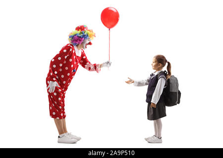 Volle Länge Profil geschossen von einem Clown mit einem roten Luftballon auf eine Schülerin auf weißem Hintergrund Stockfoto