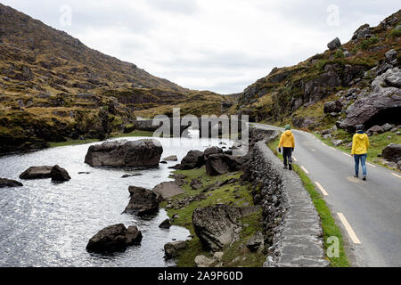 Mutter und Sohn gehen durch den Fluss Loe, schmale Straße durch die Lücke der Dunloe Tal in der macgillycuddy Reeks Berge, Irland, County Kerry. Stockfoto