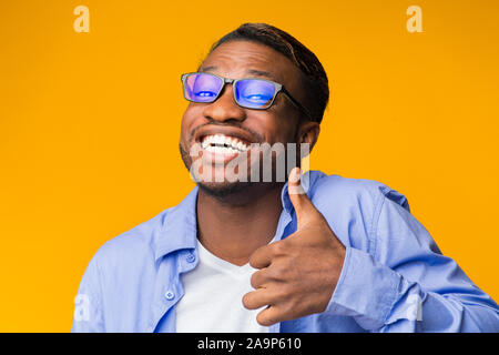 Lustige Schwarzer Mann deutete Daumen hoch stehend, Studio Shot Stockfoto