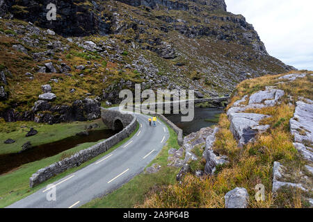 Mutter und Sohn gehen durch den Fluss Loe, schmale Straße durch die Lücke der Dunloe Tal in der macgillycuddy Reeks Berge, Irland, County Kerry. Stockfoto